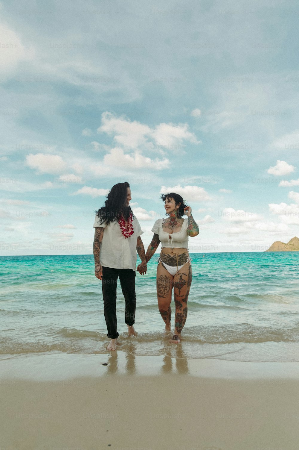 a couple of women standing on top of a sandy beach