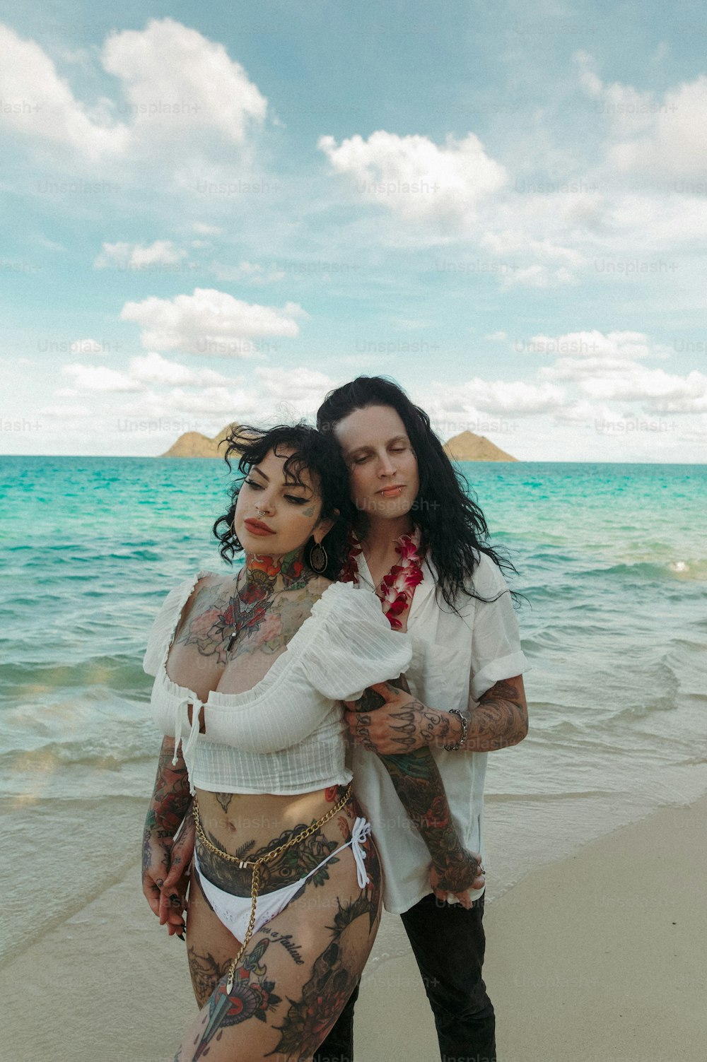 um casal de mulheres em pé um ao lado do outro em uma praia