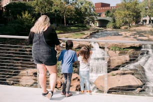 uma mulher e duas crianças olhando para uma cachoeira
