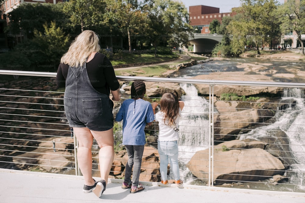 a woman and two children looking at a waterfall