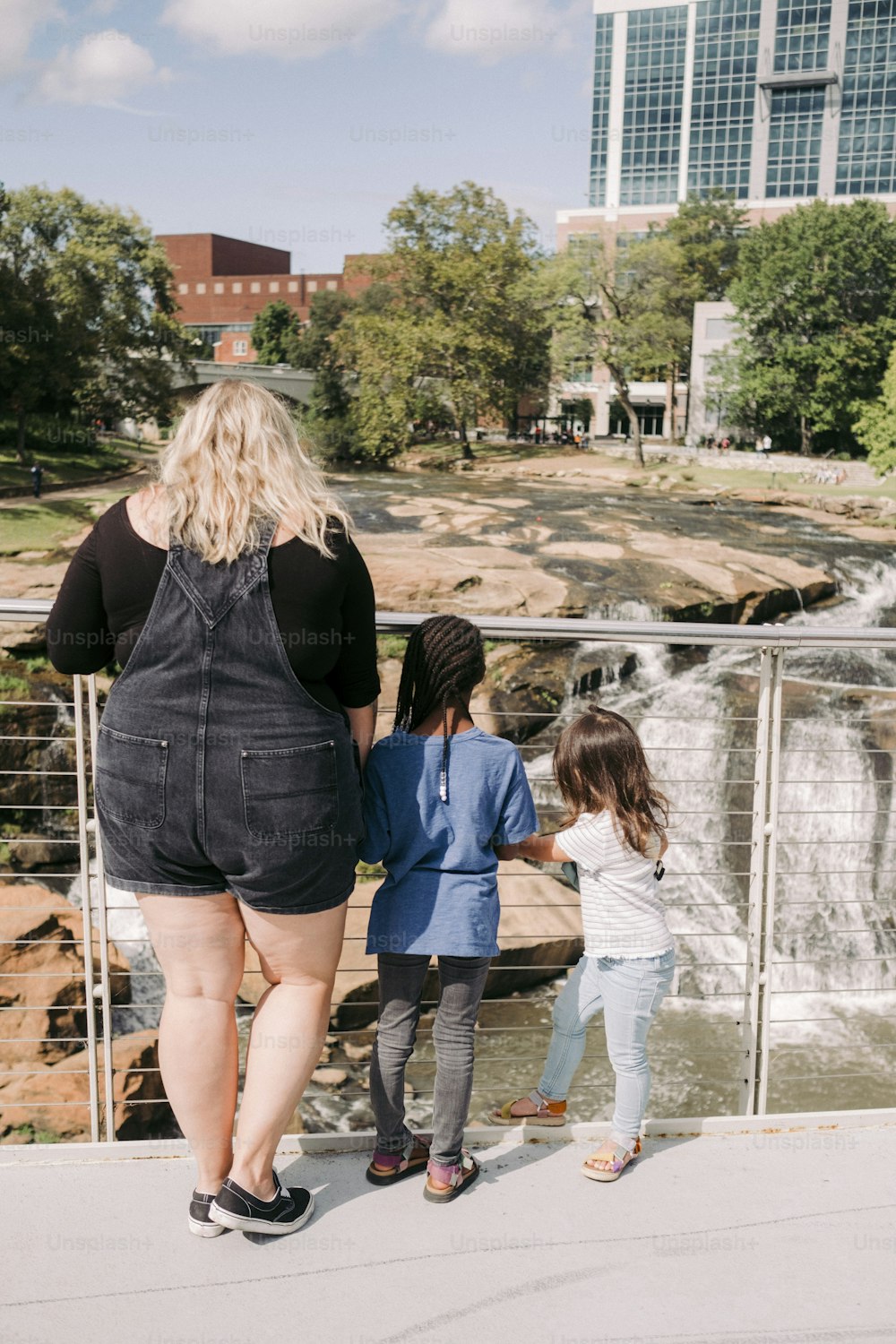 a woman and two children are looking at a waterfall