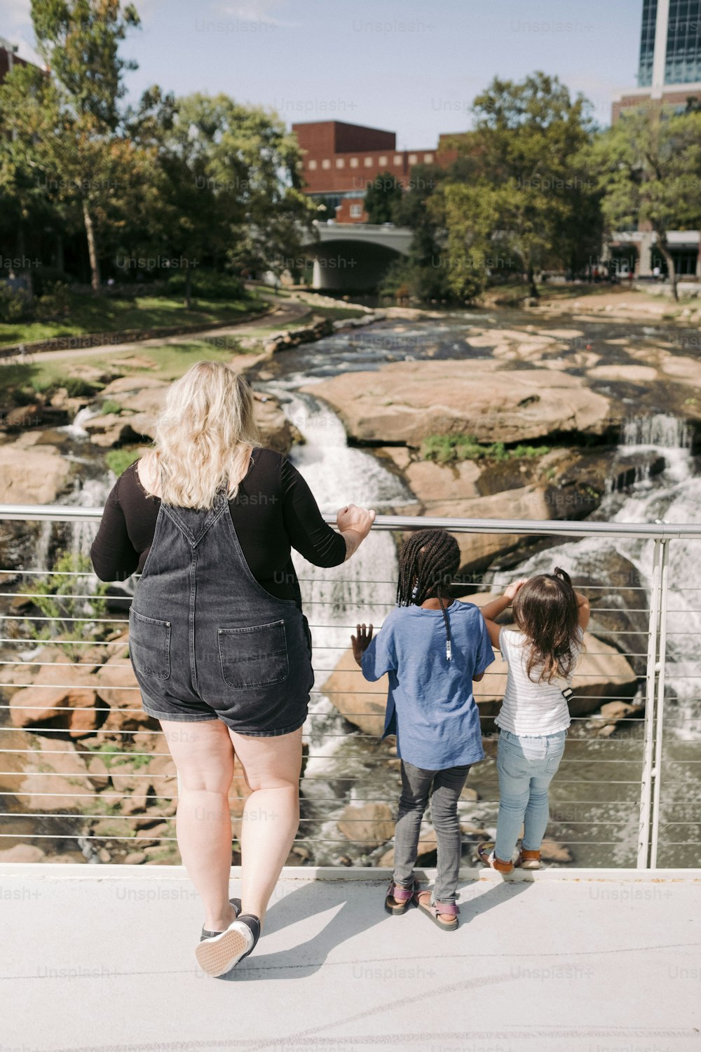 a woman and two children are walking by a waterfall