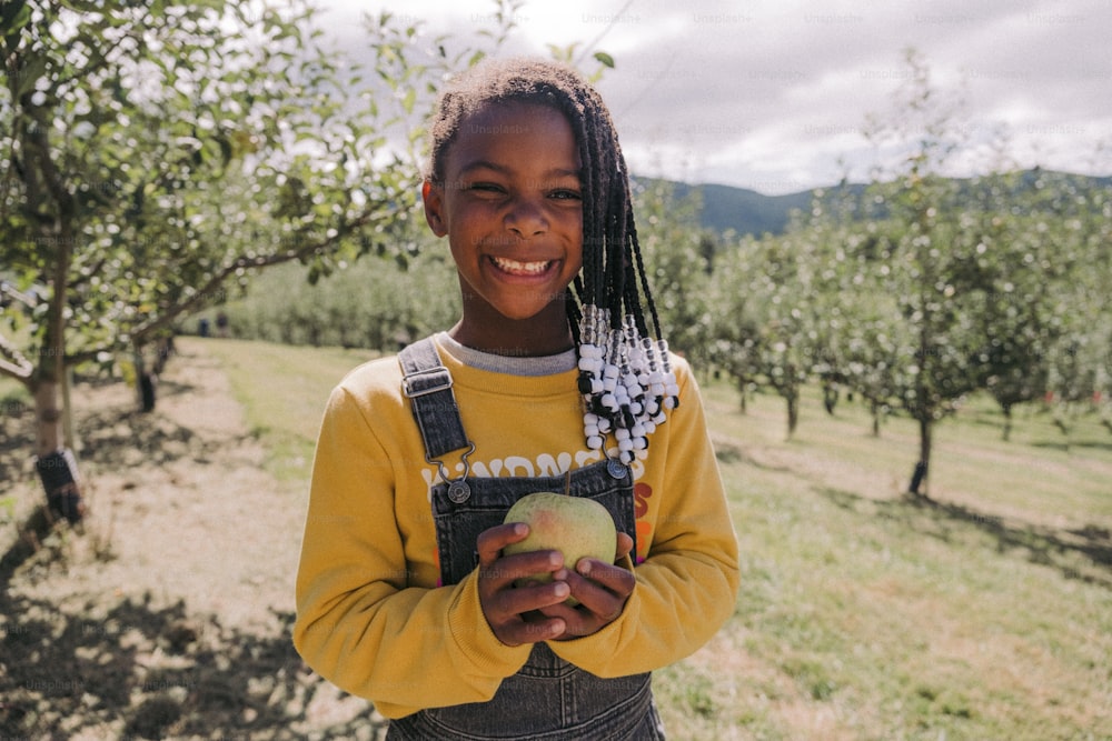 a young girl holding an apple in an apple orchard