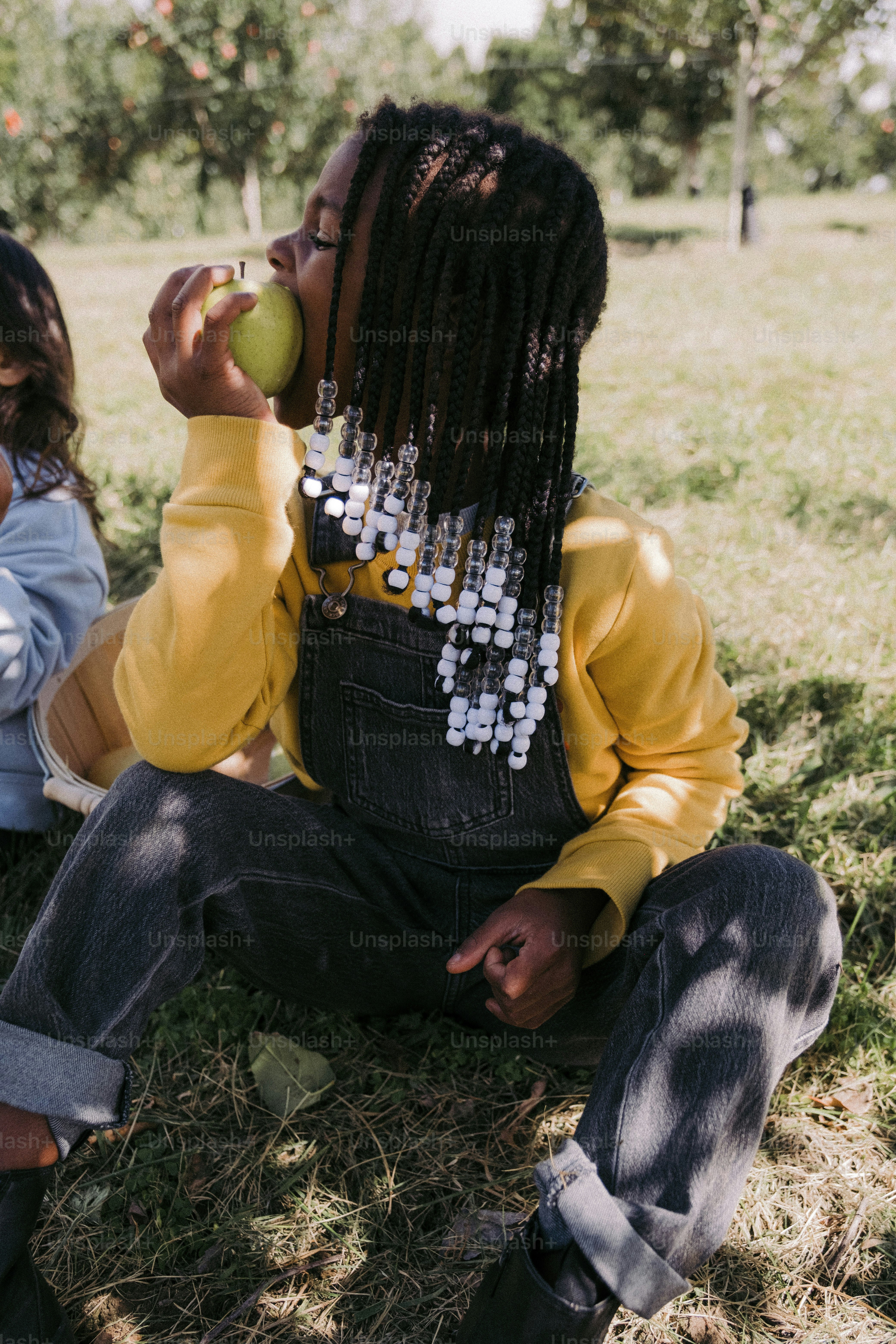 a woman sitting on the ground eating an apple