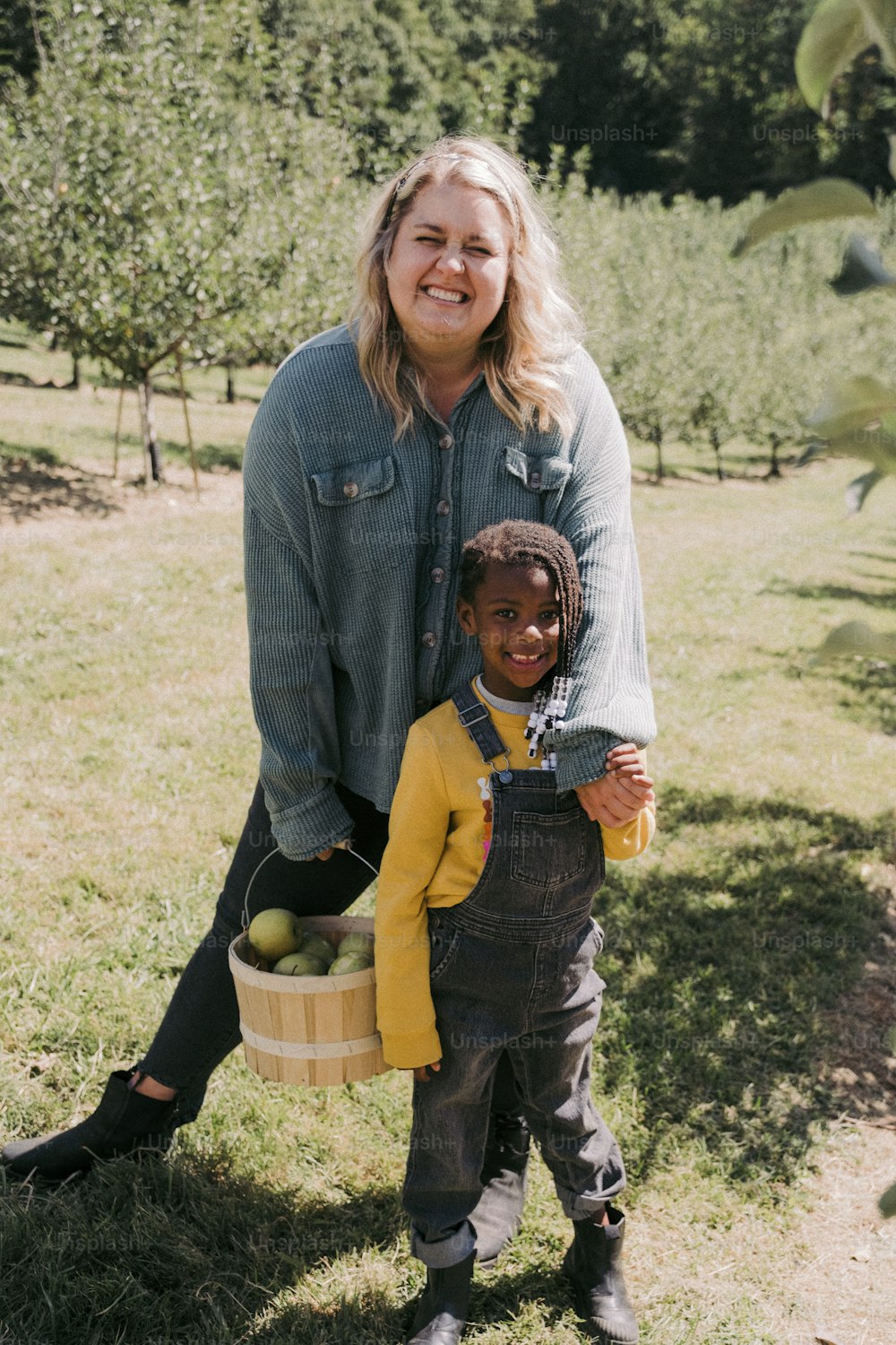 uma mulher segurando uma cesta de maçãs ao lado de uma criança