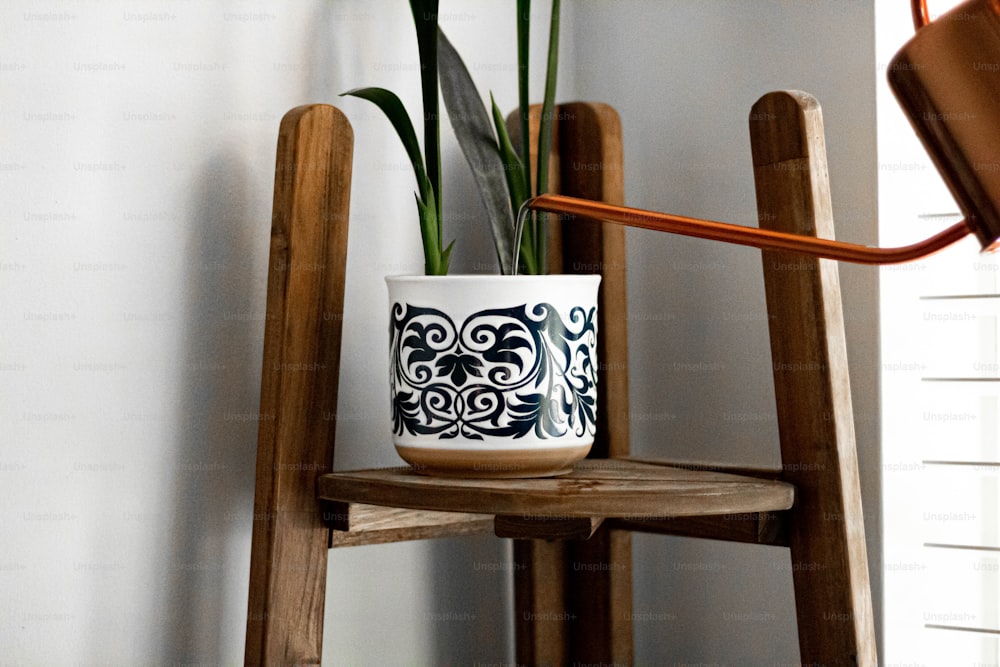 um vaso de planta sentado em cima de uma cadeira de madeira