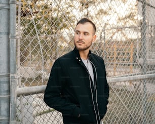 a man standing in front of a chain link fence