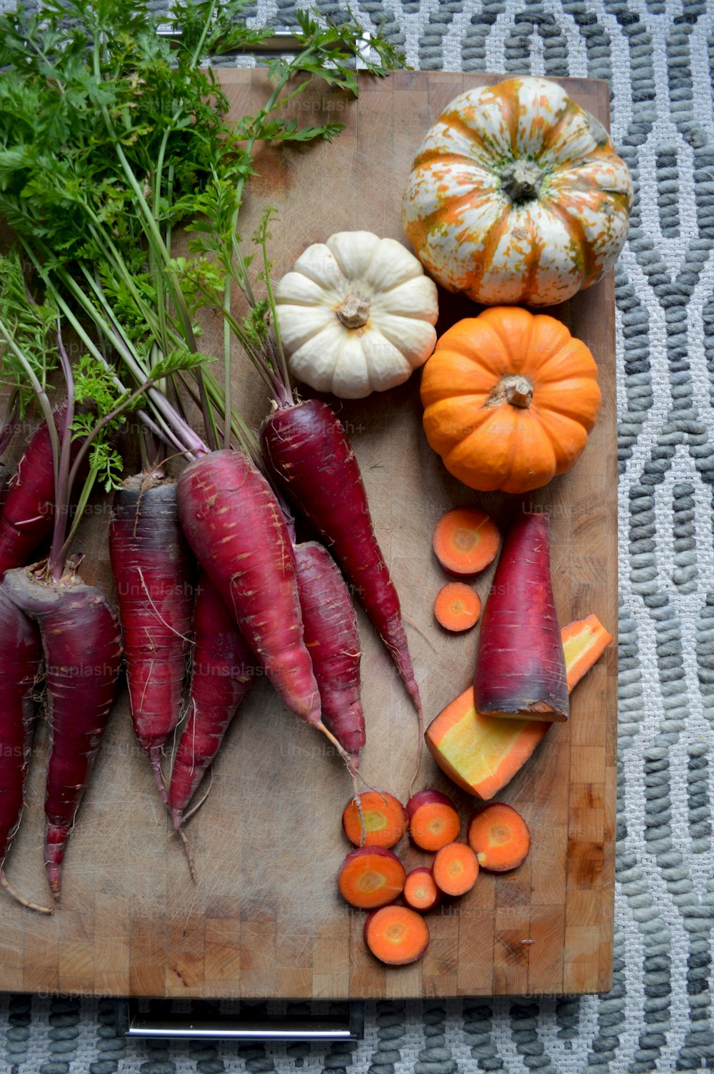 una tabla de cortar cubierta con zanahorias y otras verduras