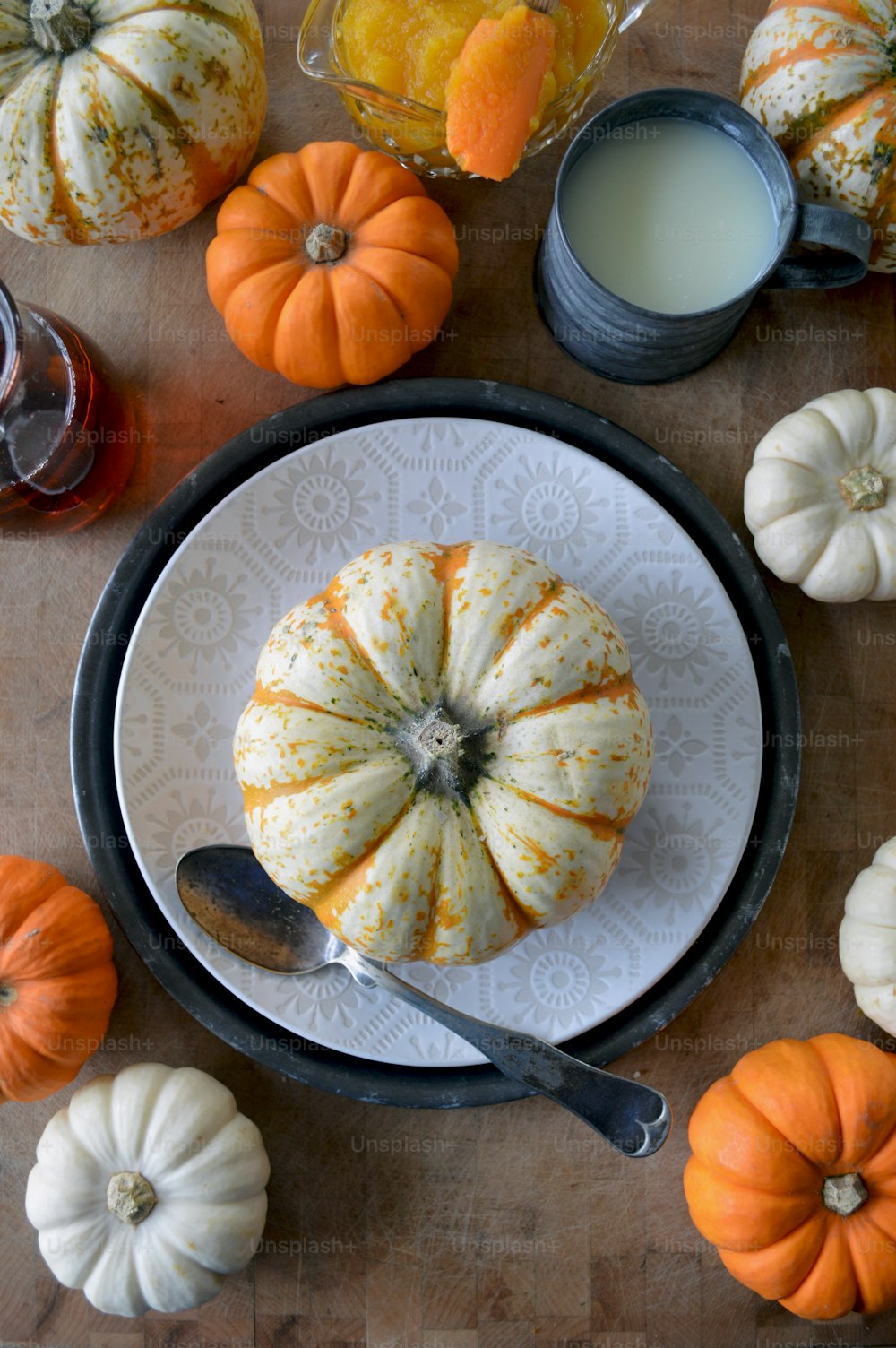 a white plate topped with a pumpkin next to a glass of milk