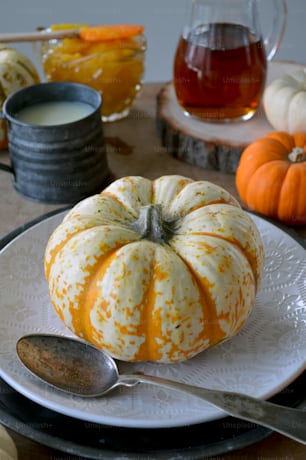 a white plate topped with a pumpkin next to a cup of tea
