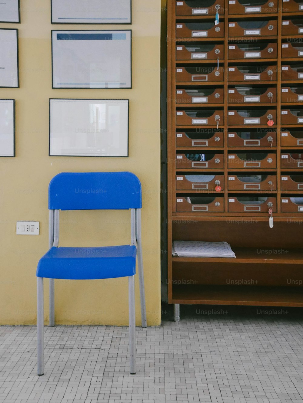 uma cadeira azul sentada em frente a uma parede cheia de gavetas