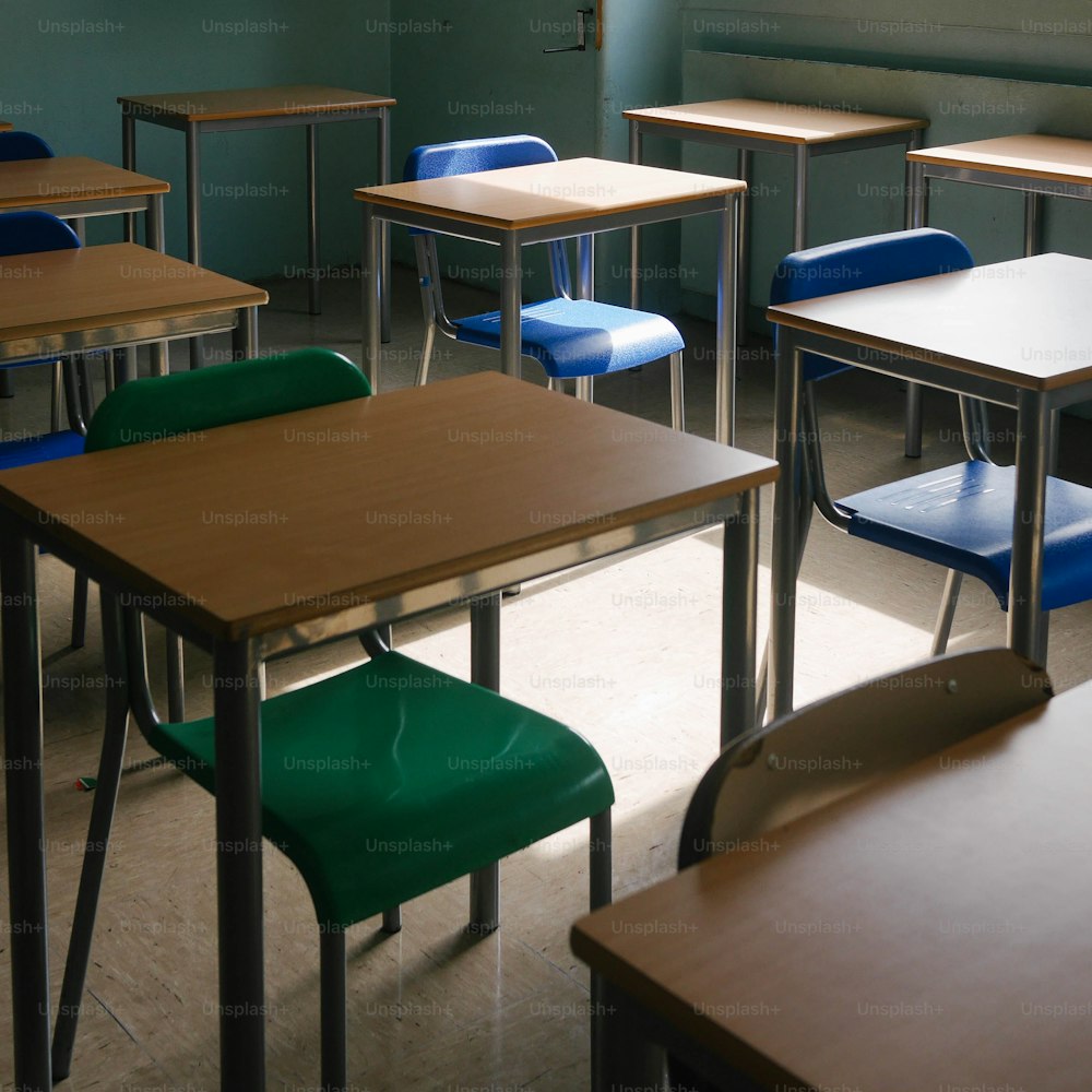a row of desks in a classroom with blue and green chairs