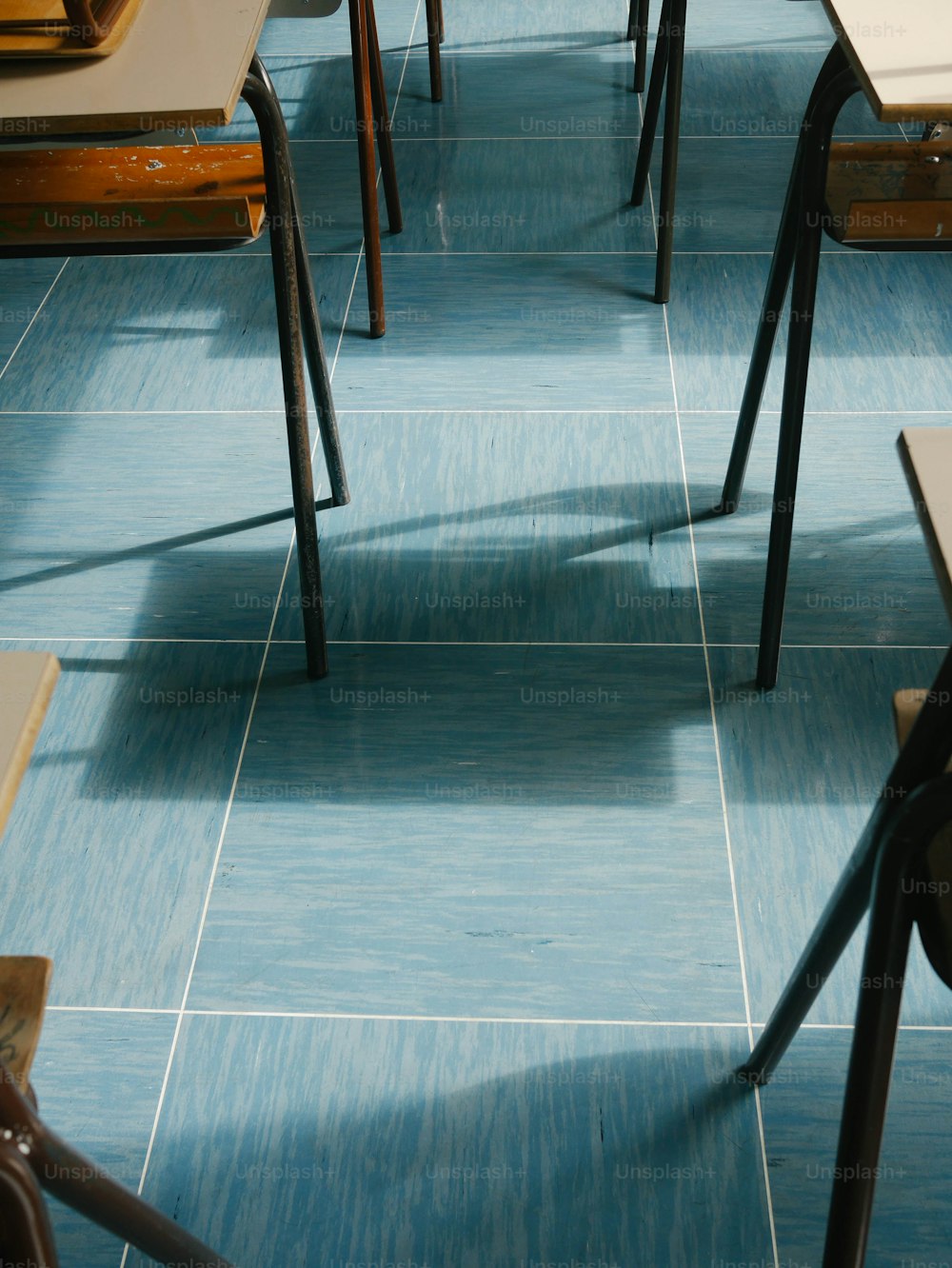 une salle de classe avec un sol bleu et des bureaux en bois