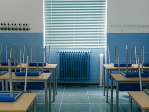 uma sala de aula com paredes azuis e carteiras de madeira