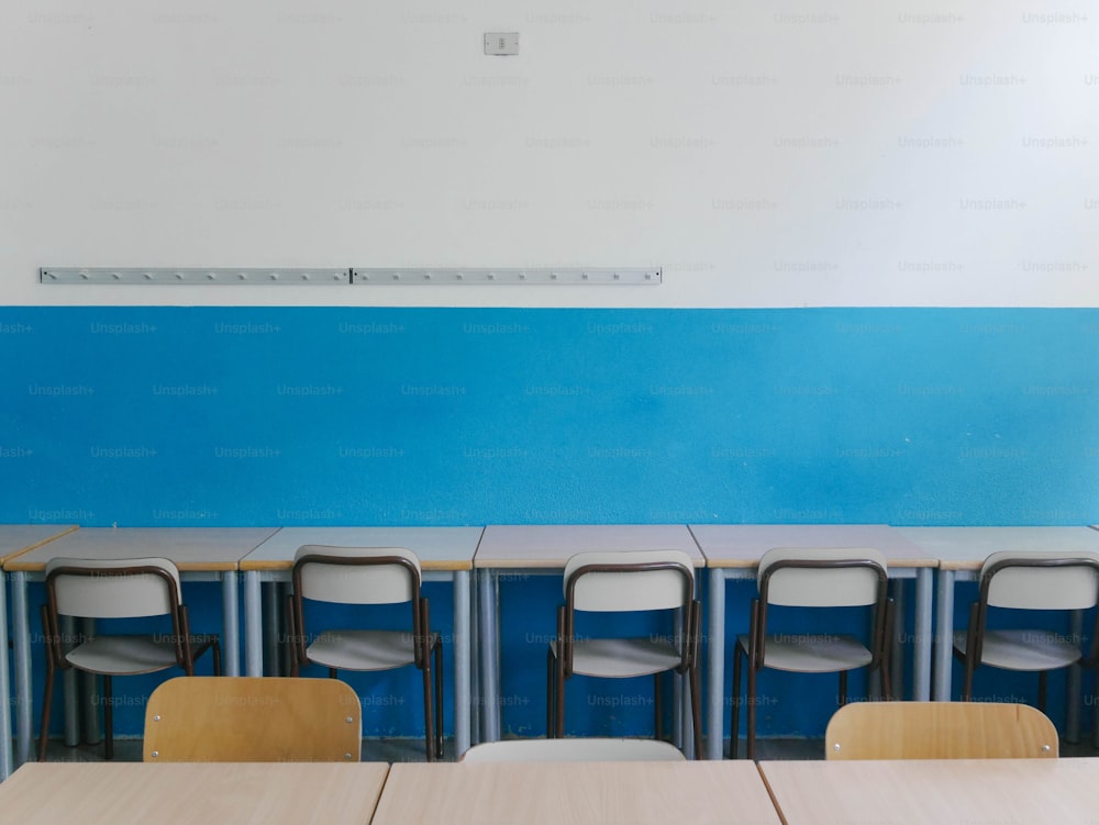 uma fileira de cadeiras sentadas em frente a uma parede azul