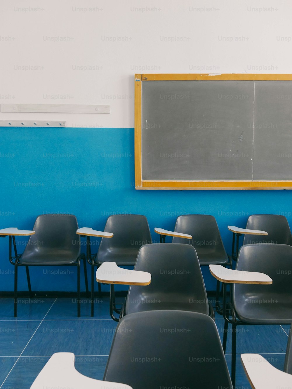 a classroom with blue walls and black chairs