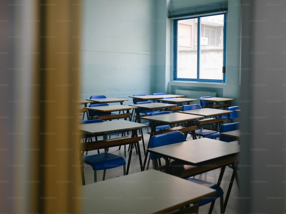 ein Klassenzimmer mit Schreibtischen und Stühlen neben einem Fenster