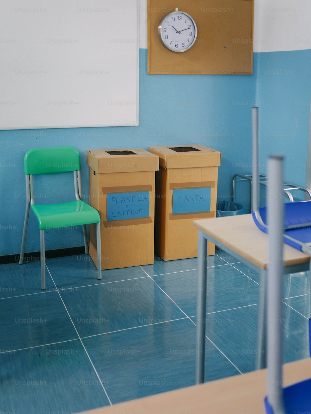 uma sala de aula com uma mesa, cadeira e um relógio na parede