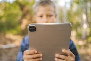 um menino segurando um tablet em suas mãos