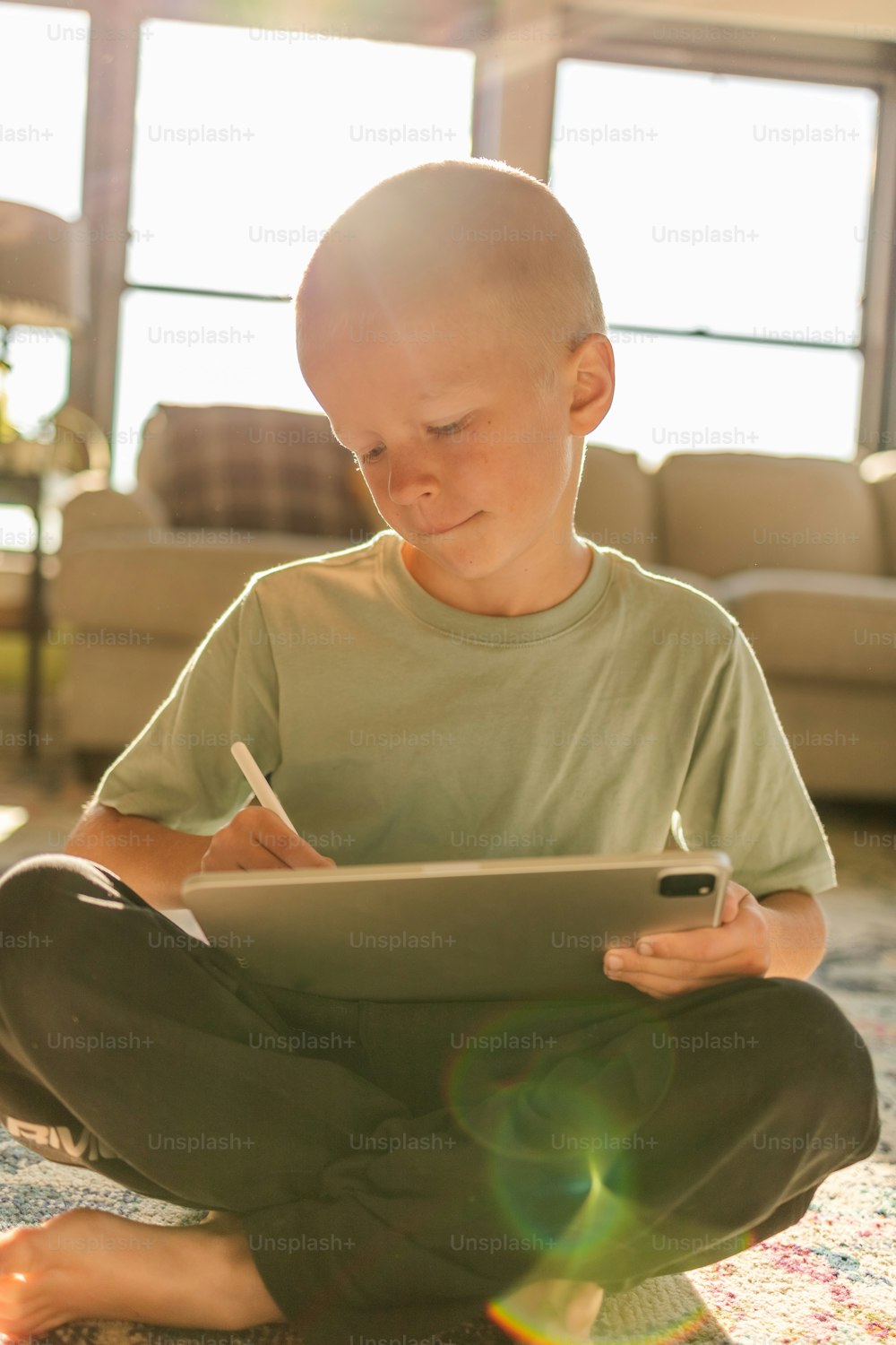 a young boy sitting on the floor using a tablet