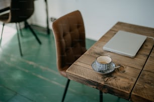 ein Holztisch mit einem Laptop neben einer Tasse Kaffee