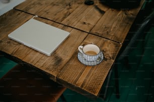 a cup of coffee and a laptop on a wooden table