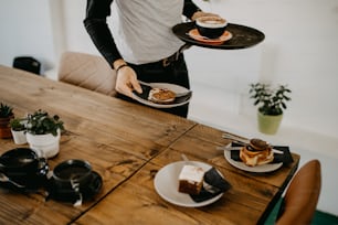 man holding two plates of food on a wooden table