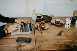 a person using a laptop on a wooden table