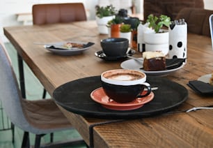 une table en bois surmontée d’une assiette de nourriture et d’une tasse de café
