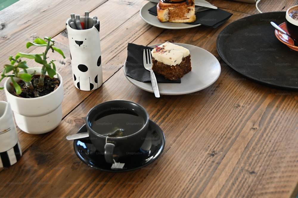 a wooden table topped with plates of food and cups of coffee