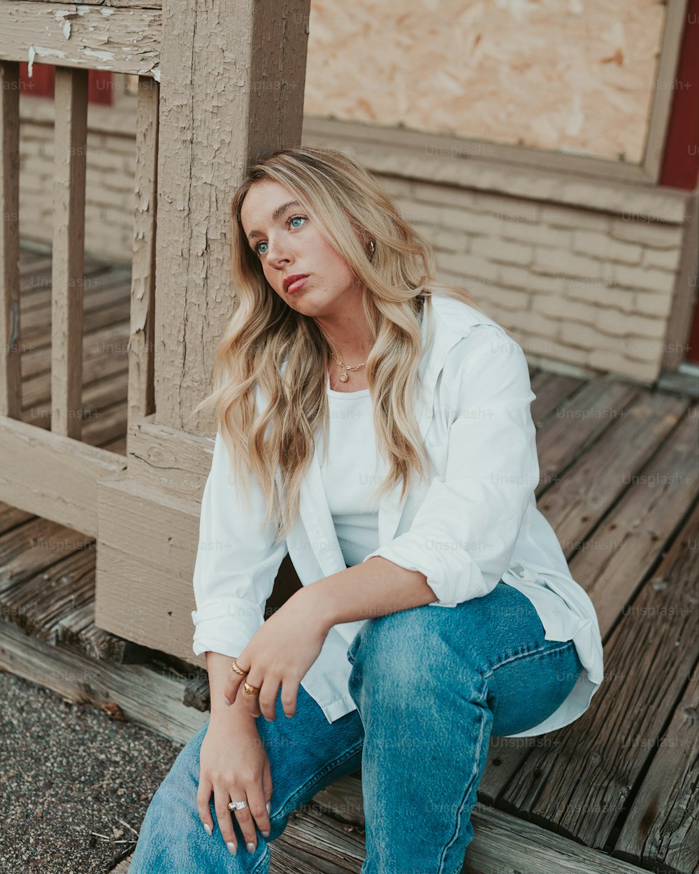 a woman sitting on a porch with her legs crossed