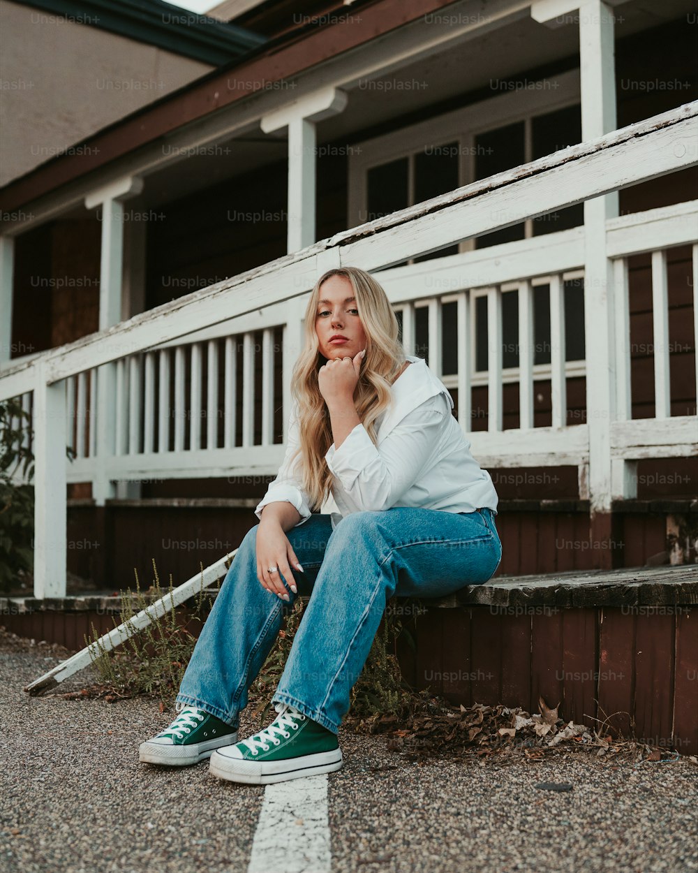 a woman sitting on a curb with her hand on her chin