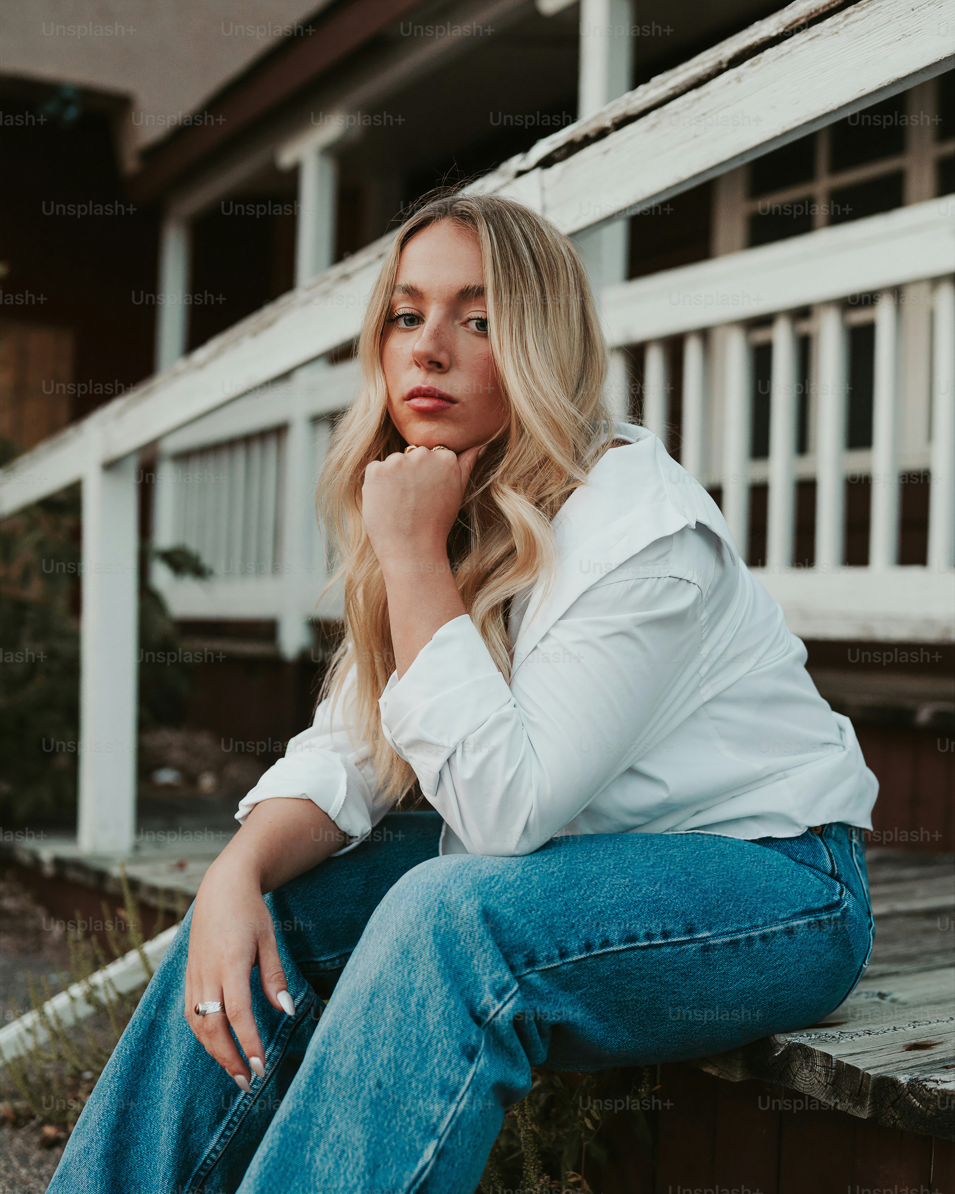 A woman sitting on the ground with her hand on her chin photo ...