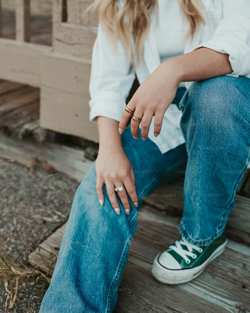 a woman sitting on a porch wearing a white shirt and jeans