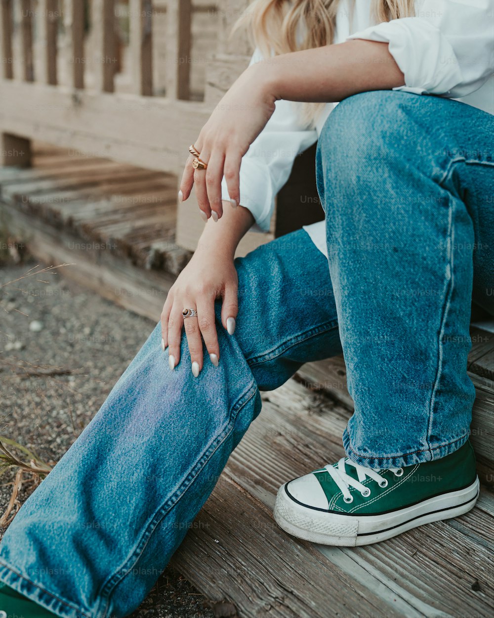 a woman sitting on a wooden bench with her hands on her knees