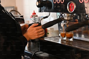 eine Person, die eine Kaffeemaschine benutzt, um ein Getränk zuzubereiten