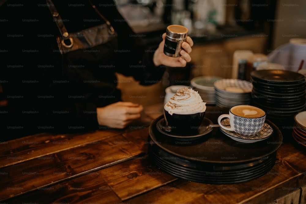 uma pessoa segurando uma xícara de café em cima de uma mesa de madeira