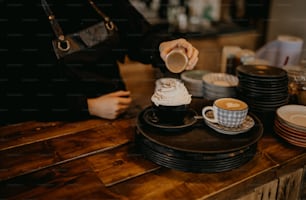 eine Person, die eine Tasse Kaffee auf einen Holztisch gießt