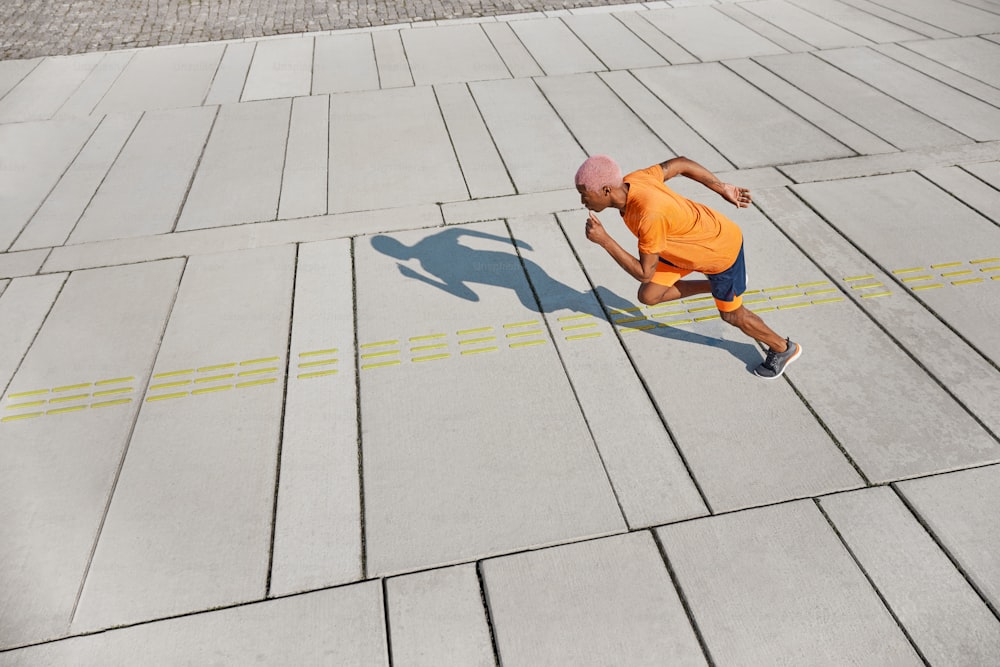 Um homem de camisa laranja está correndo em uma calçada