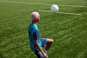 Un hombre con un sombrero rosa está jugando con una pelota de fútbol