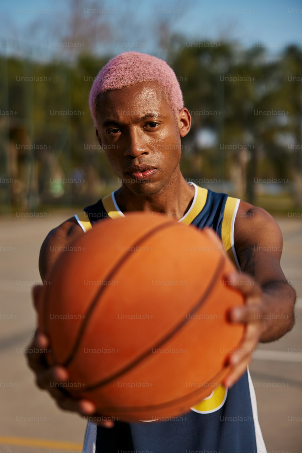um homem com cabelo rosa segurando uma bola de basquete