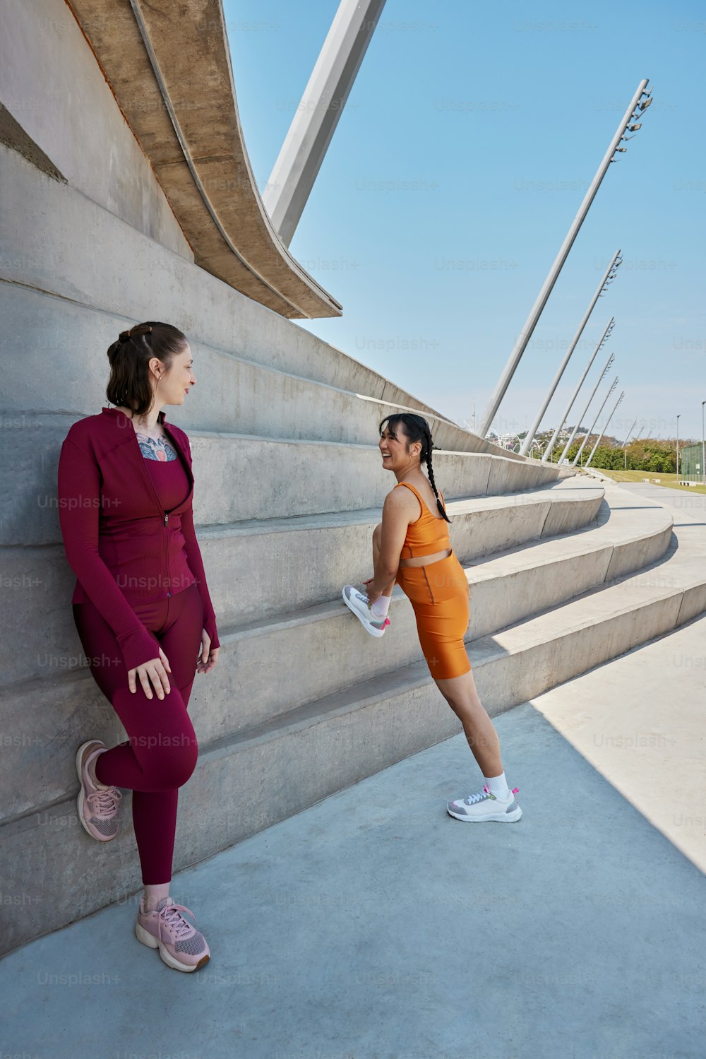 Zwei Frauen in Sportkleidung lehnen sich an eine Wand