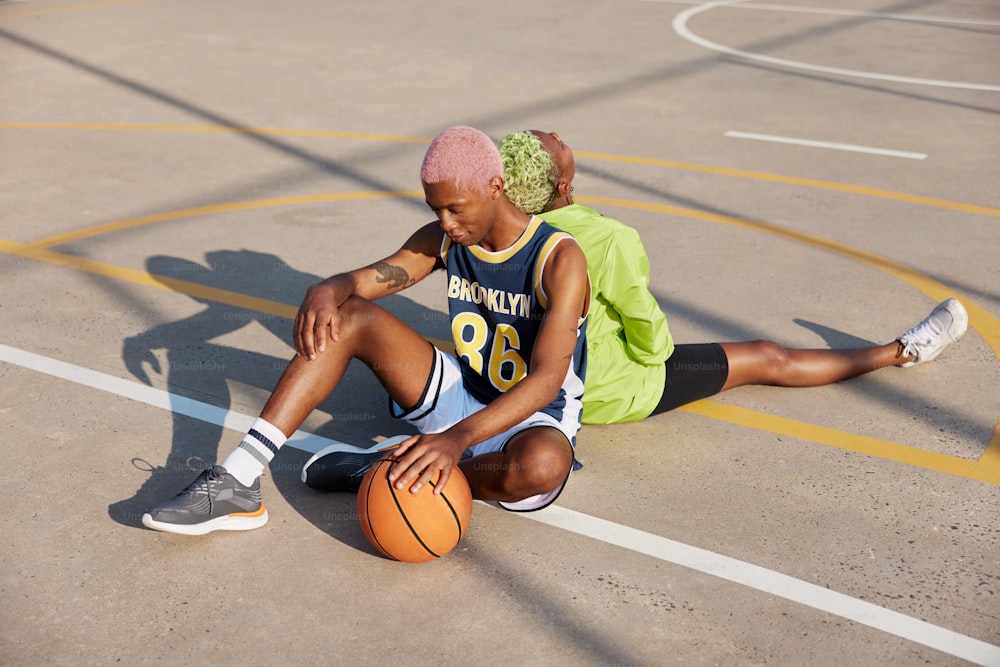 um casal de pessoas sentadas em cima de uma quadra de basquete