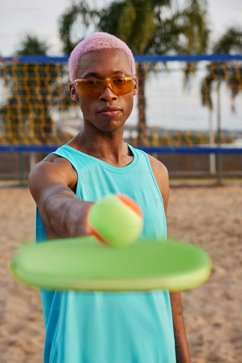 Un hombre con una camiseta azul sin mangas sosteniendo un frisbee verde
