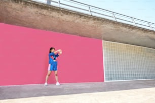 Eine Frau, die vor einer rosafarbenen Wand steht