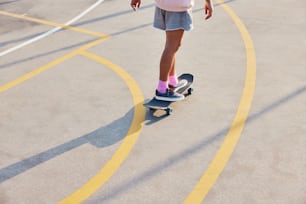 a young girl riding a skateboard on a parking lot