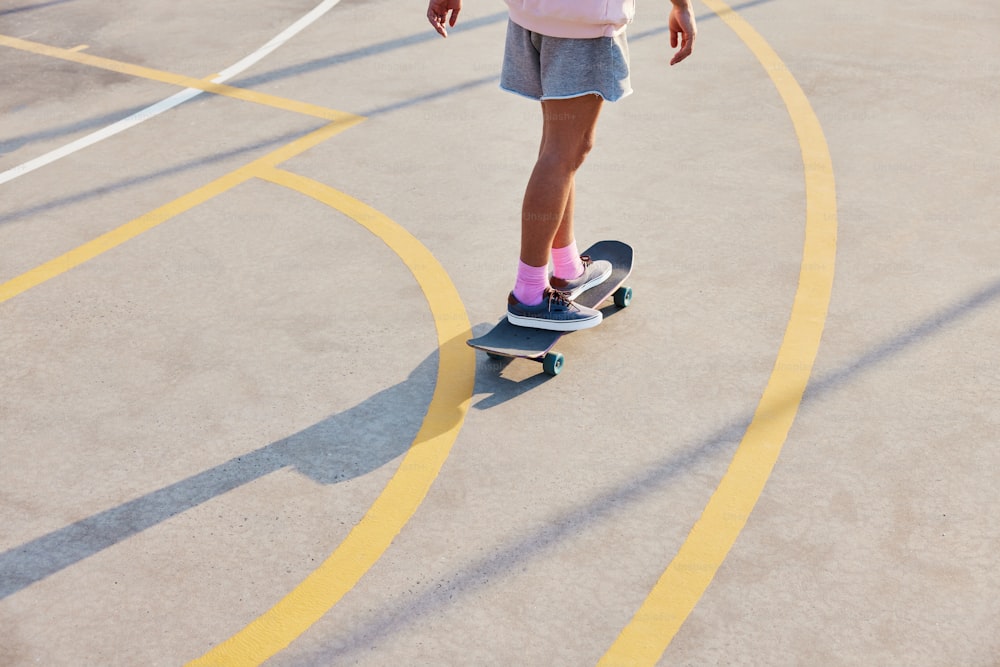 uma jovem montando um skate em um estacionamento