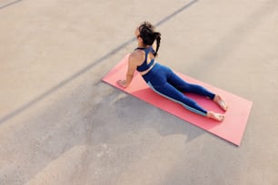 uma mulher está fazendo yoga em um tapete rosa