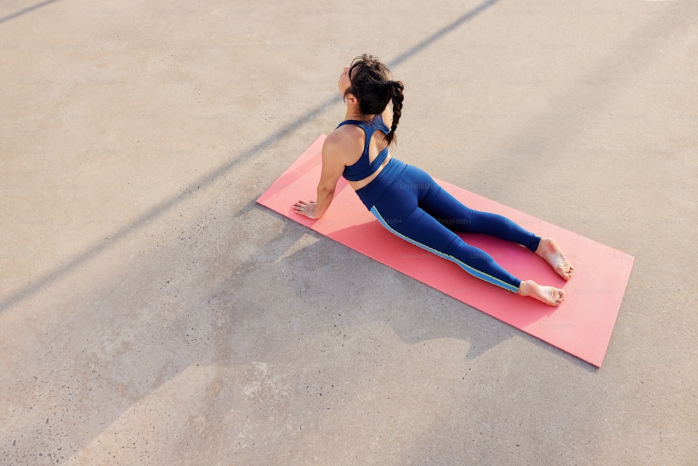 Una donna sta facendo yoga su un tappetino rosa