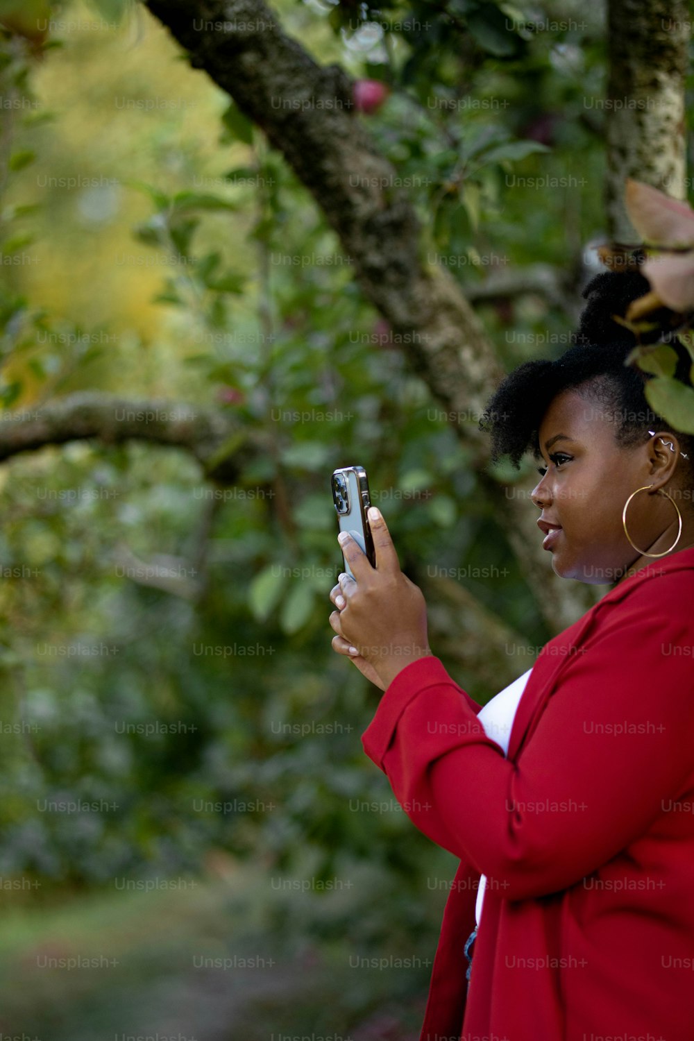 a woman standing in front of a tree holding a cell phone